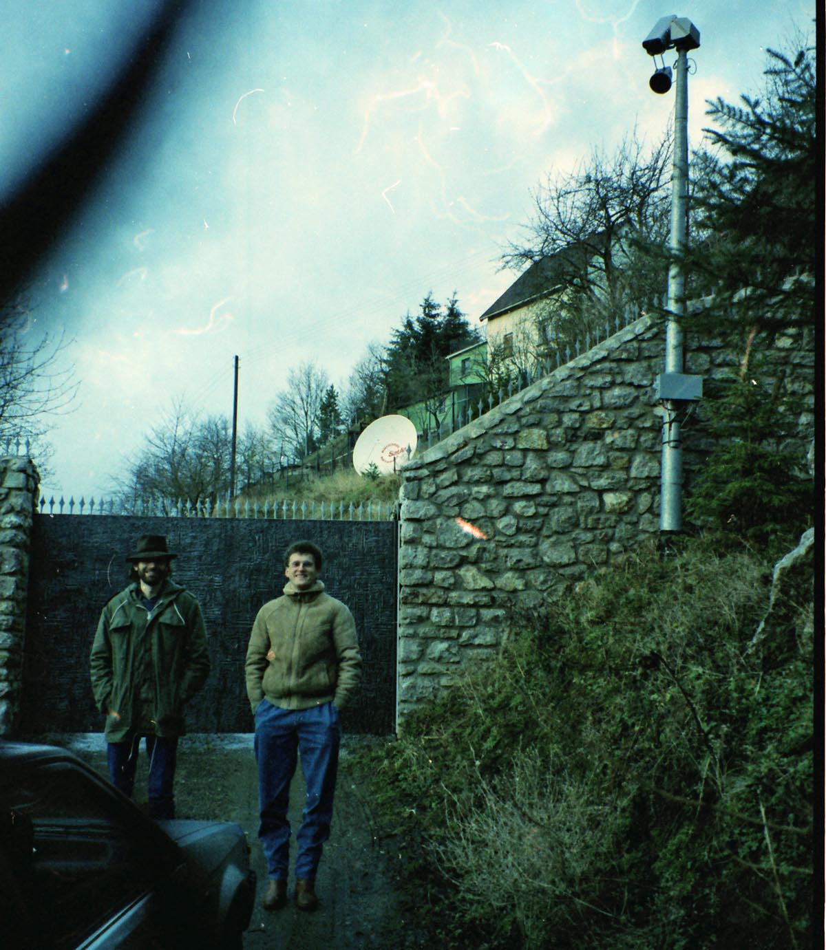 1986, Martin Sczech und Werner Wanger machen einen Spaziergang um die weiträumige Umzäunung der Villa Mauss im Hunsrück. Die Überwachungskameras sind immer auf Sendung.