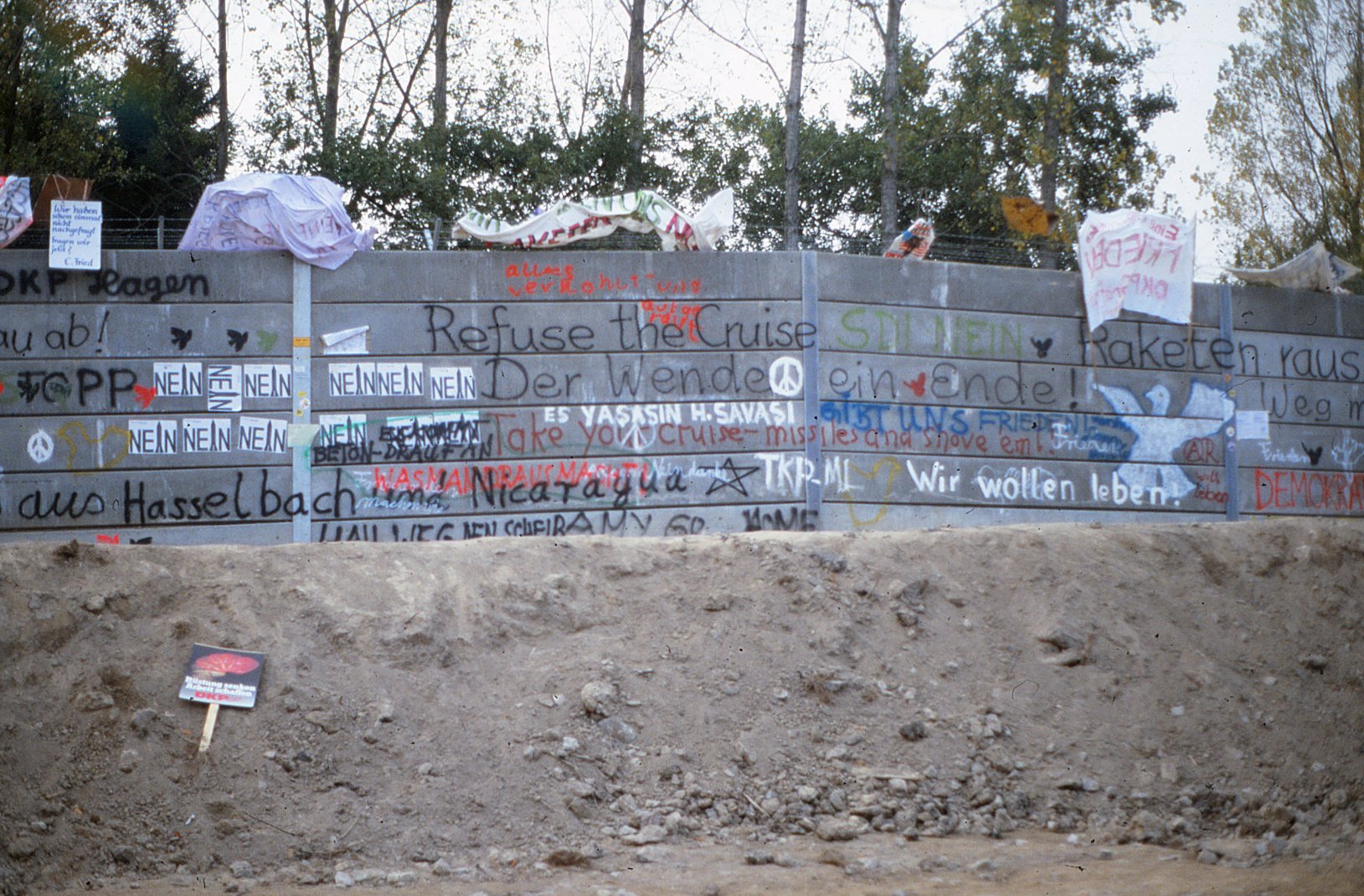 Betonmauer mit Aufschriften: Refuse the Cruise, Der Wende ein Ende, Wir wollen leben